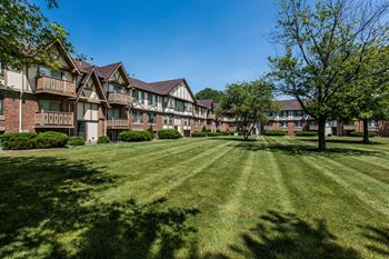 An apartment building with green grass and trees